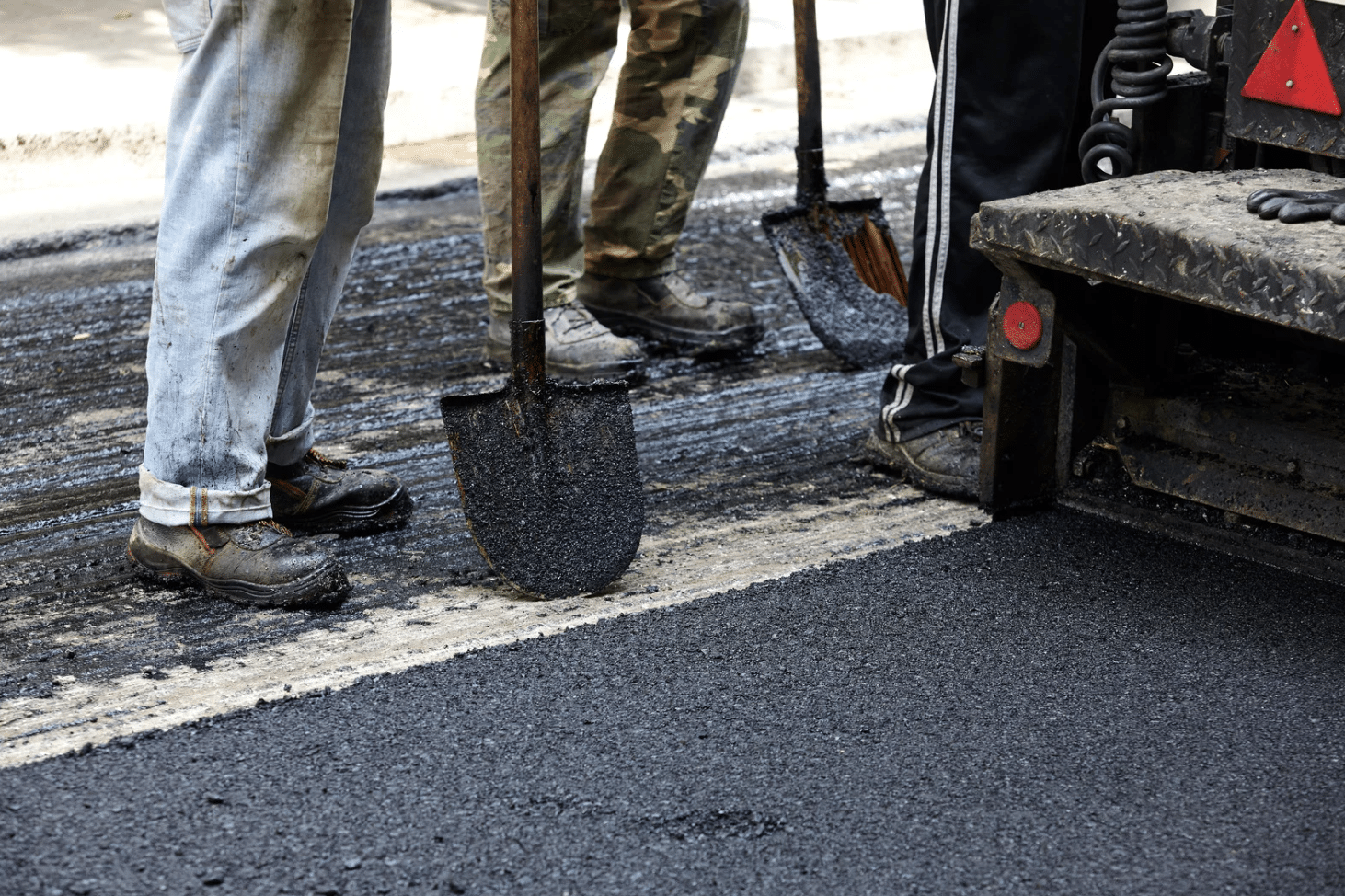 workers suing asphalt paving tools during road construction