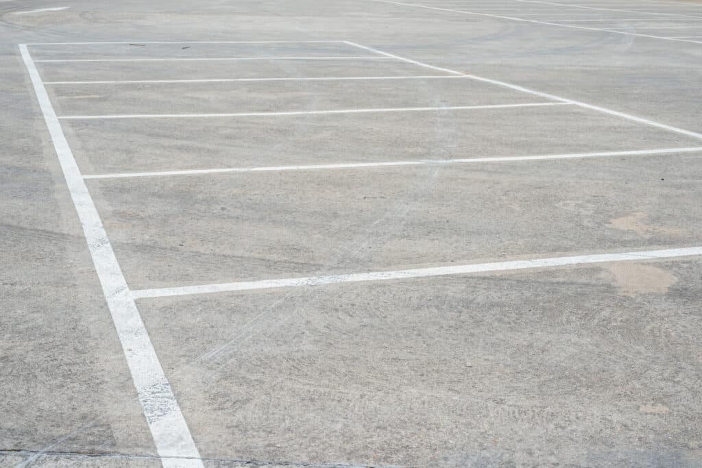 faded, gray asphalt parking lot with stripes